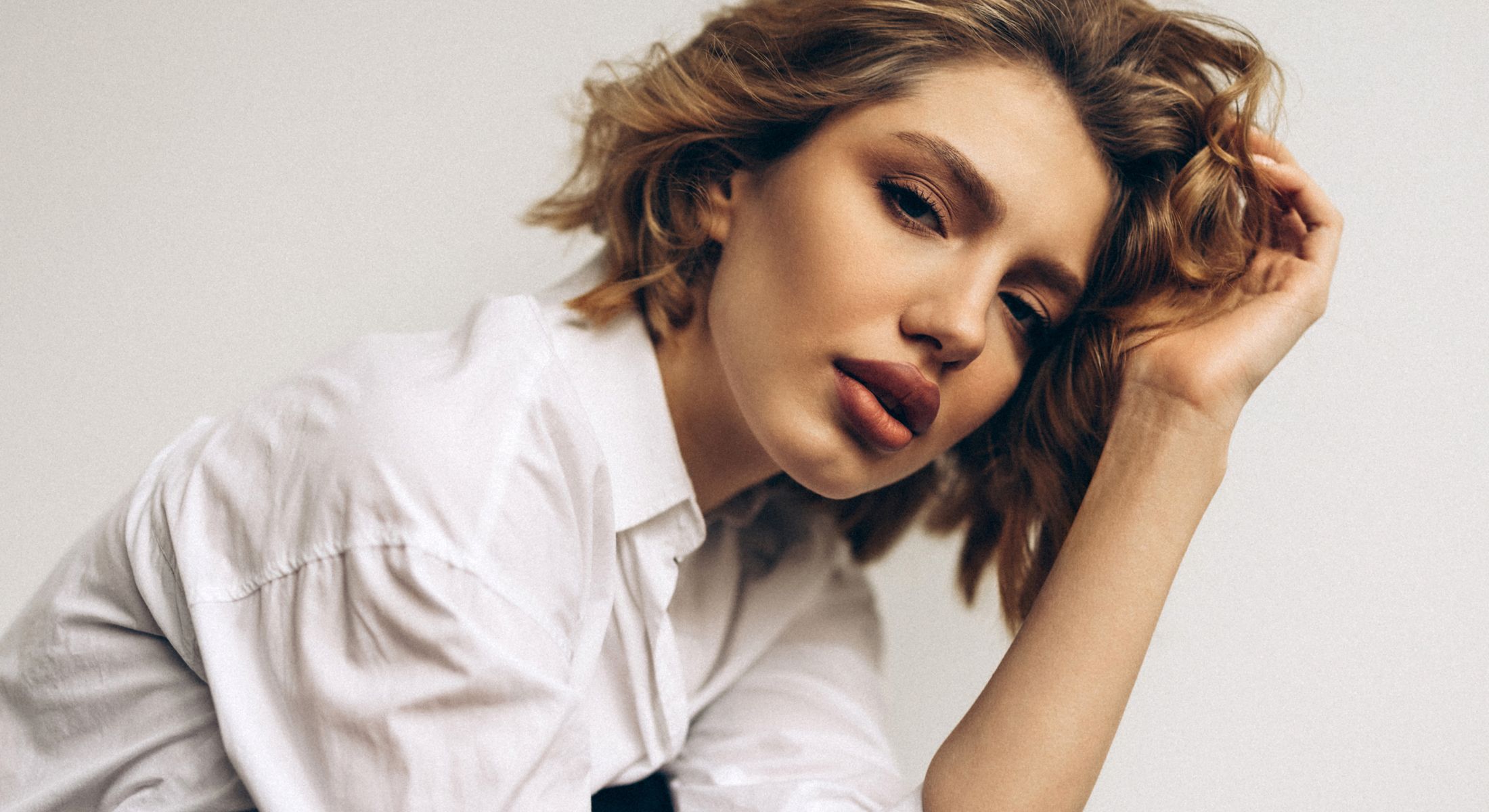 Woman with tousled hair in white shirt.