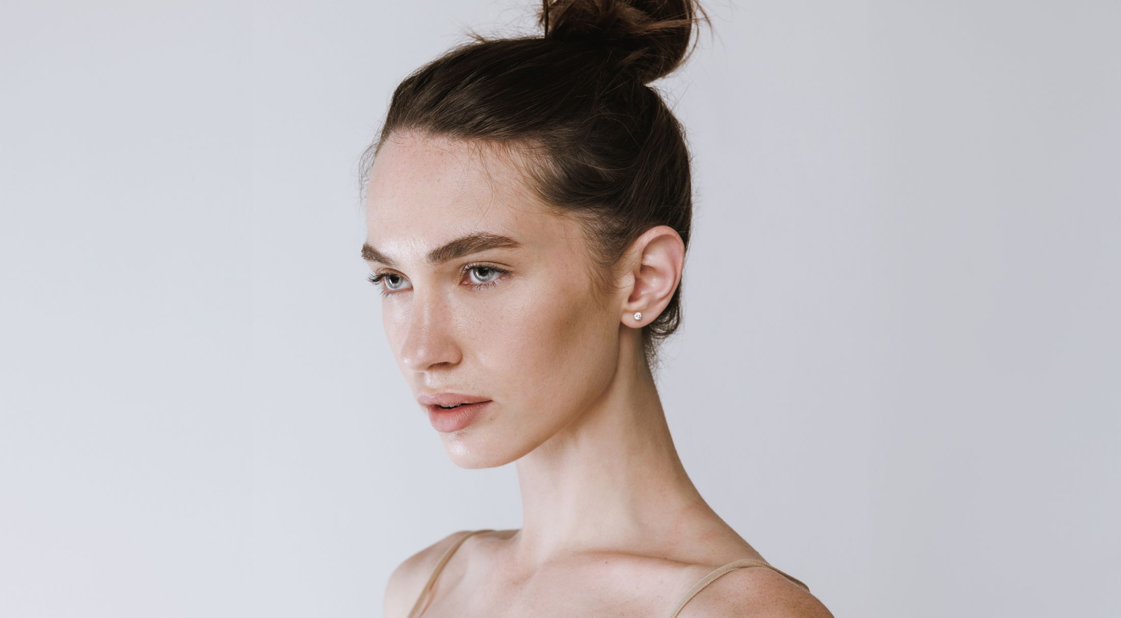 Woman with bun hairstyle against plain background.