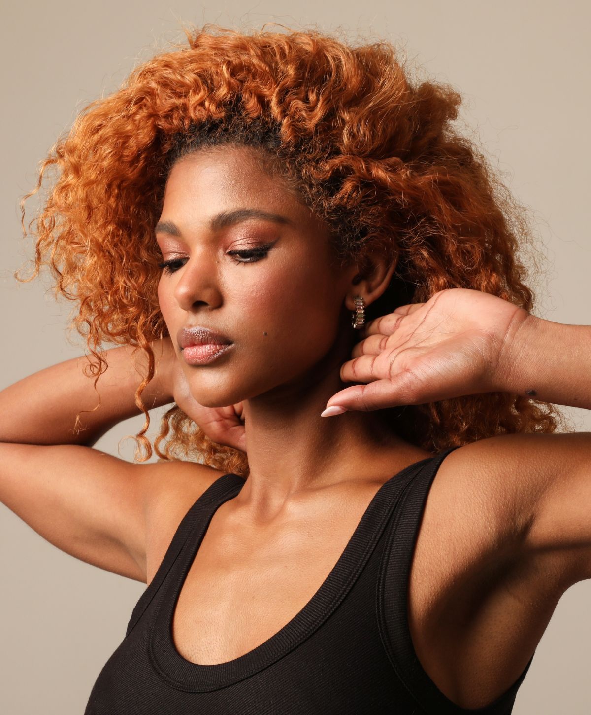 Model with curly hair in black tank top.